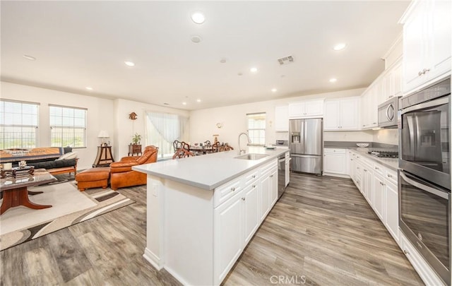 kitchen with light wood finished floors, white cabinets, stainless steel appliances, and a sink