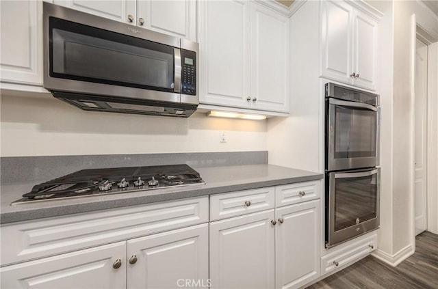 kitchen with white cabinets, appliances with stainless steel finishes, and dark wood-type flooring