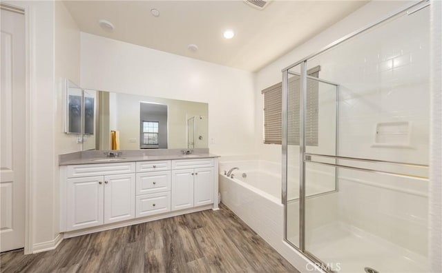 bathroom with a bath, a shower stall, wood finished floors, and a sink