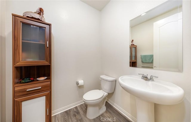 bathroom featuring toilet, wood finished floors, and baseboards