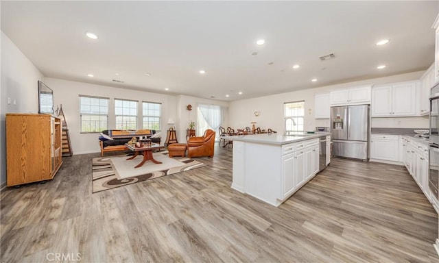 kitchen with visible vents, a sink, light wood-style floors, stainless steel refrigerator with ice dispenser, and open floor plan