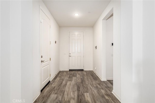 hallway featuring baseboards and dark wood-type flooring