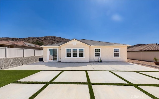 rear view of house featuring a mountain view, stucco siding, a patio, and a fenced backyard