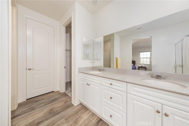 bathroom featuring double vanity, visible vents, wood finished floors, and a sink