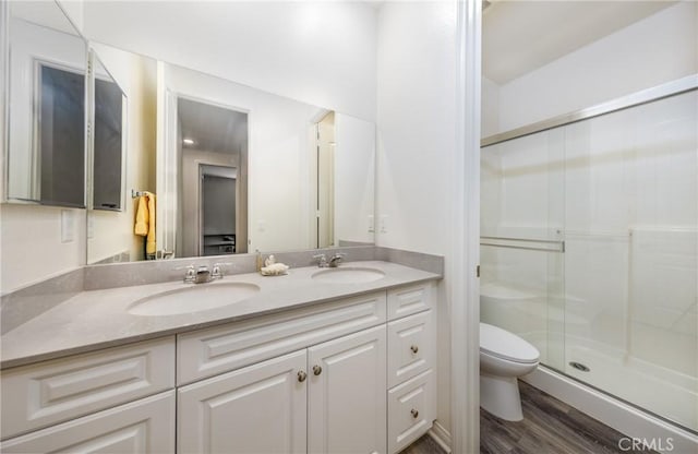 full bath with a shower stall, toilet, double vanity, and a sink