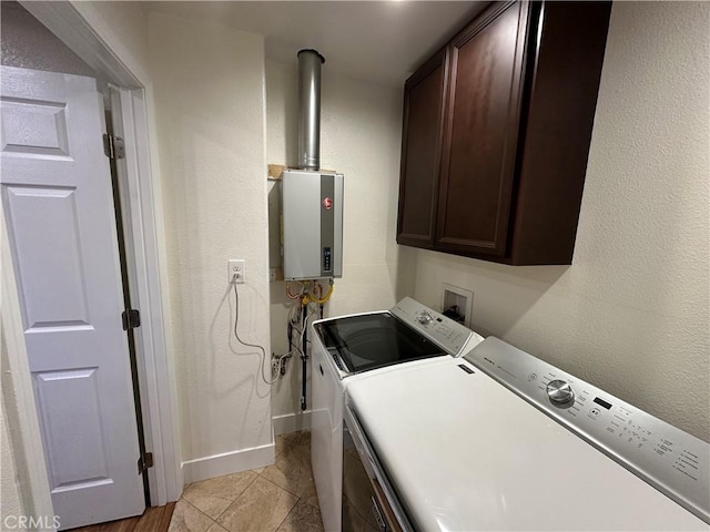 washroom featuring baseboards, light tile patterned flooring, cabinet space, water heater, and washer and clothes dryer