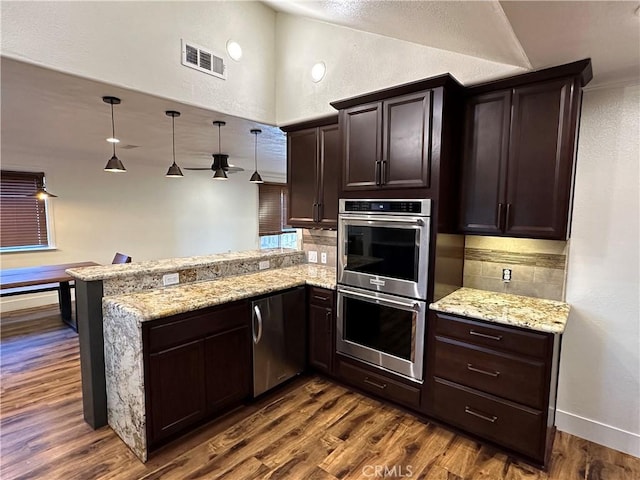 kitchen with visible vents, dark brown cabinets, a peninsula, dark wood-style floors, and stainless steel appliances