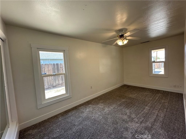 empty room featuring visible vents, baseboards, ceiling fan, and dark carpet