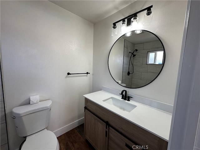 bathroom featuring toilet, wood finished floors, a shower, baseboards, and vanity