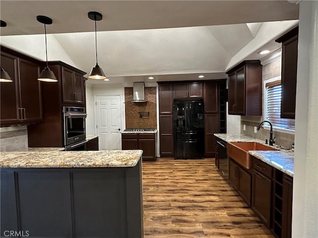 kitchen featuring appliances with stainless steel finishes, lofted ceiling, wall chimney range hood, and a sink