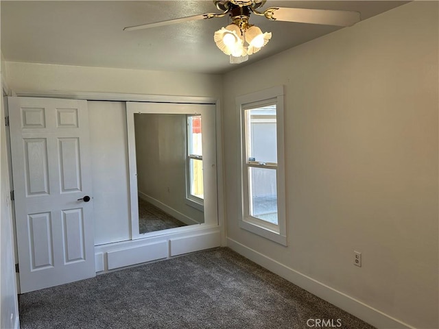 unfurnished bedroom featuring baseboards, dark colored carpet, a closet, and ceiling fan