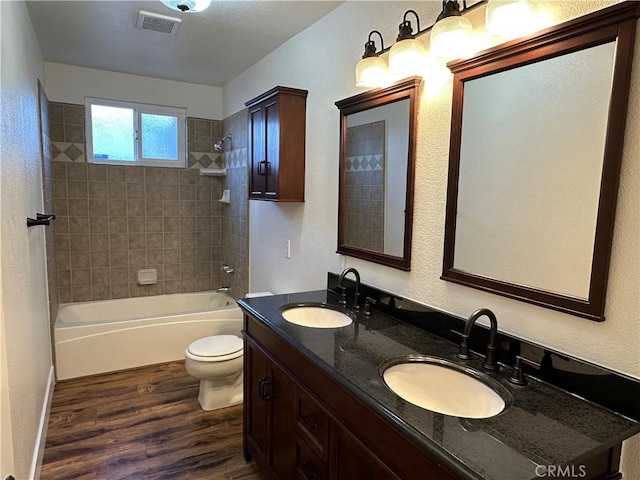 full bathroom with toilet, wood finished floors, visible vents, and a sink