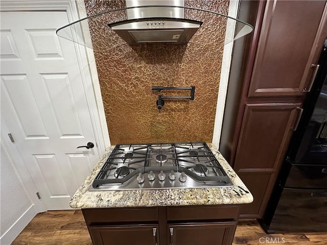 room details featuring stainless steel gas cooktop, dark wood-style floors, light stone countertops, and decorative backsplash