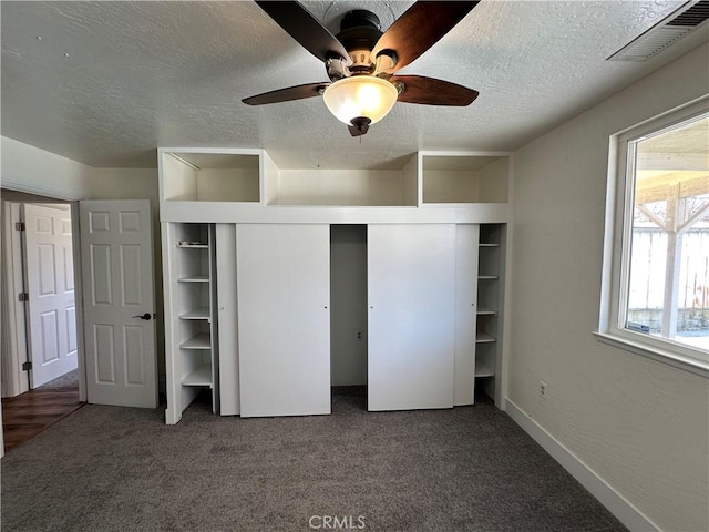 unfurnished bedroom with carpet, visible vents, ceiling fan, a closet, and a textured ceiling