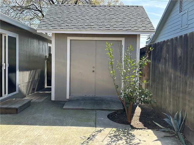 property entrance with fence and a shingled roof