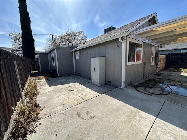back of property with a patio, a fenced backyard, and roof with shingles