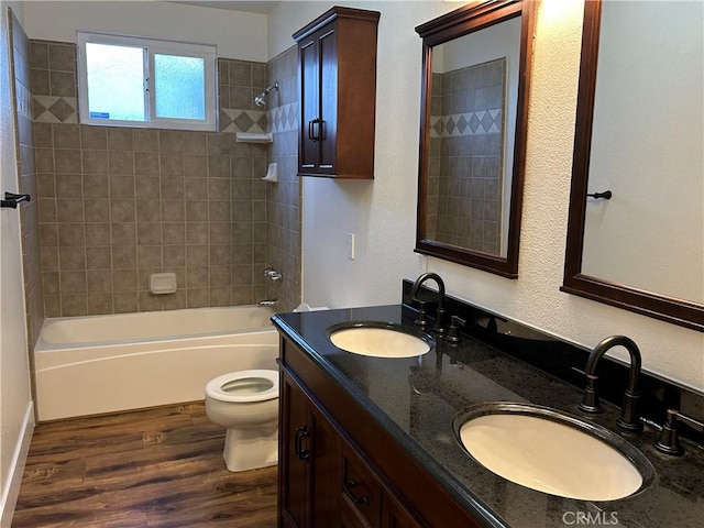 full bathroom with a sink, toilet, shower / washtub combination, and wood finished floors