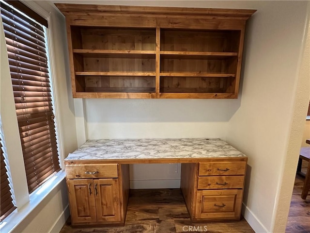 home office with baseboards, dark wood-type flooring, and built in desk