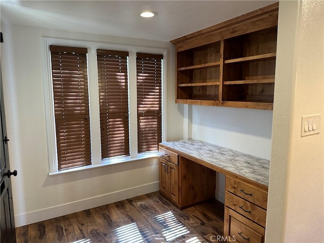 unfurnished office with dark wood finished floors, recessed lighting, built in study area, and baseboards