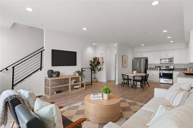 living room with stairs, recessed lighting, and light wood-style floors