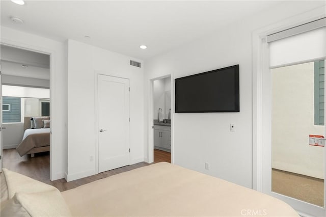 bedroom with visible vents, recessed lighting, ensuite bathroom, and wood finished floors