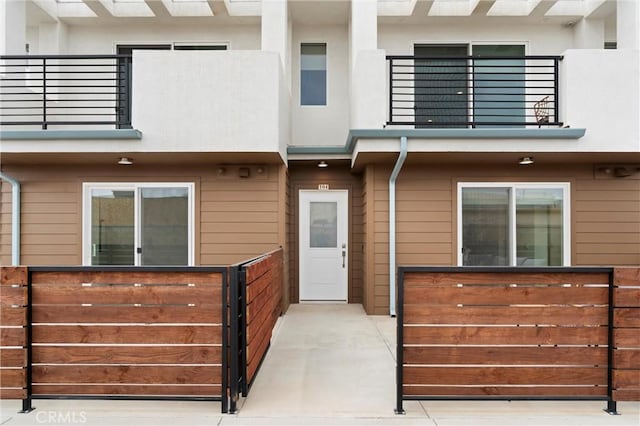 view of front of house featuring a balcony and fence