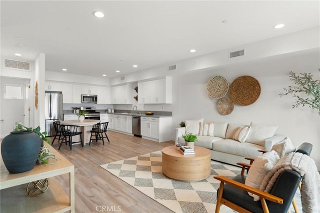 living area with recessed lighting, visible vents, and light wood-style flooring