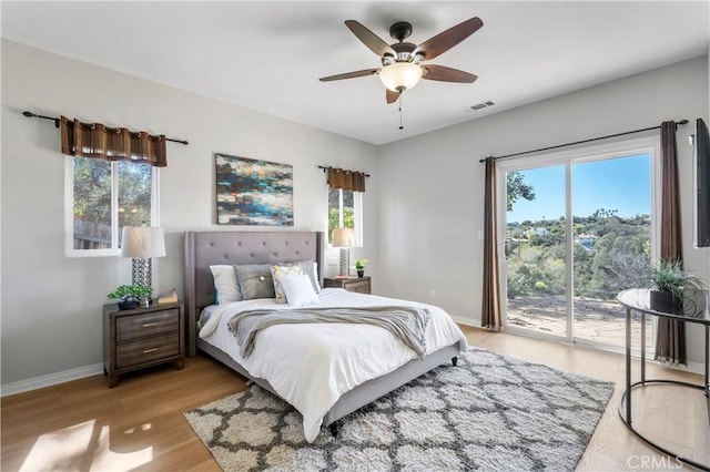 bedroom with access to exterior, multiple windows, visible vents, and light wood-type flooring