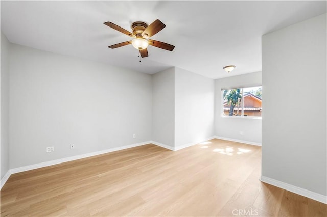 spare room with light wood finished floors, a ceiling fan, and baseboards