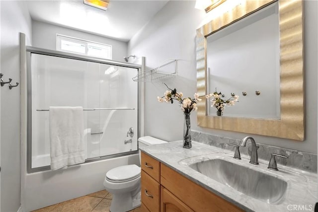 bathroom with tile patterned floors, enclosed tub / shower combo, toilet, and vanity