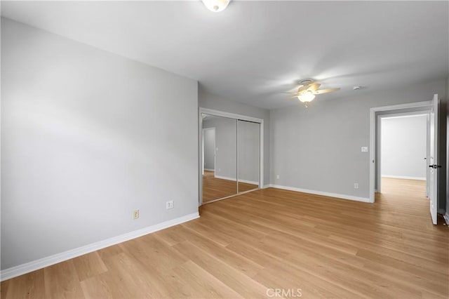 unfurnished bedroom with a closet, baseboards, a ceiling fan, and light wood finished floors