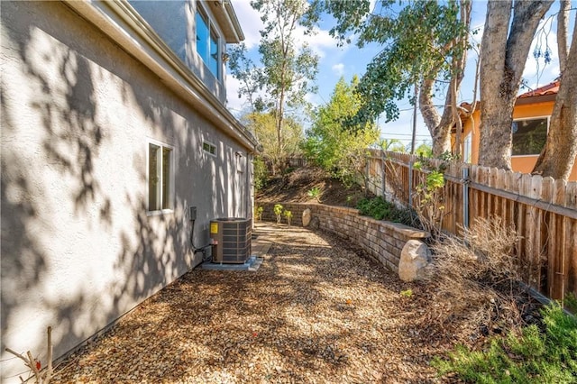 view of yard featuring central AC and fence