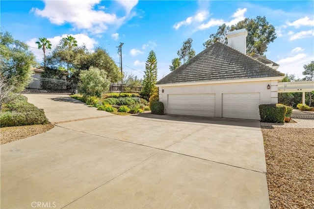 view of side of home with fence, a chimney, stucco siding, concrete driveway, and a garage