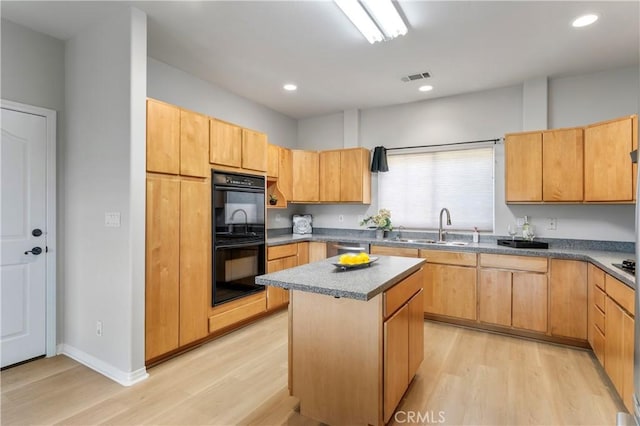 kitchen with a sink, light wood-style flooring, visible vents, and dobule oven black