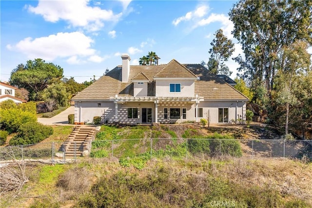 back of house featuring stucco siding, a fenced backyard, a chimney, and a pergola