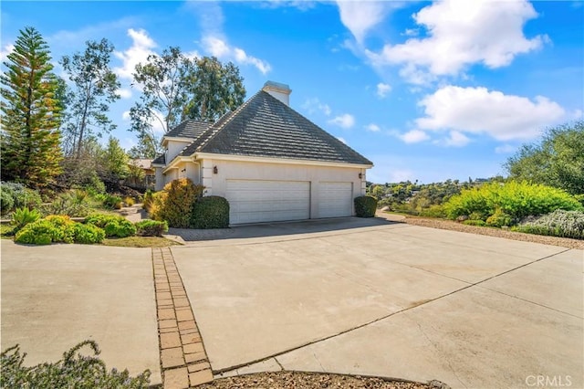 view of side of home with stucco siding, driveway, and a garage