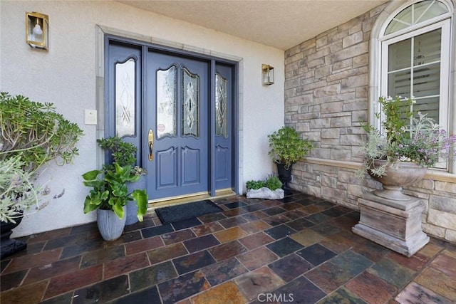 entrance to property with stone siding and stucco siding