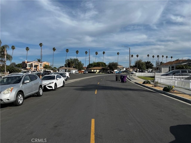 view of street featuring a residential view, curbs, street lights, and sidewalks