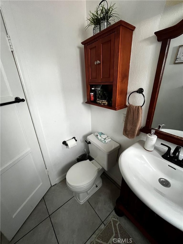 bathroom with a sink, toilet, and tile patterned flooring