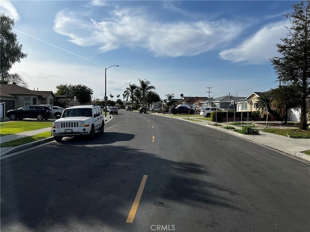 view of street with sidewalks, a residential view, curbs, and street lighting