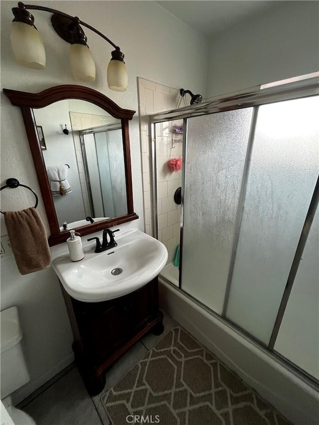 bathroom with a shower with shower door and a sink