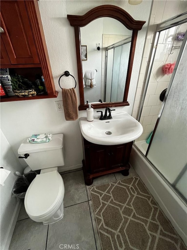 full bath with vanity, baseboards, tile patterned flooring, toilet, and combined bath / shower with glass door