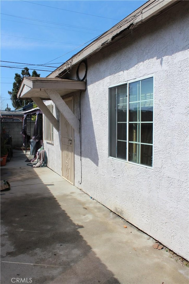 exterior space with a patio area, fence, and stucco siding