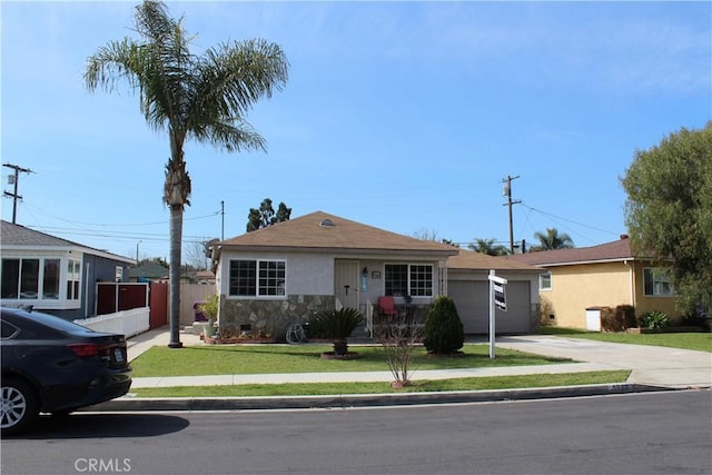 view of front facade featuring stucco siding, driveway, fence, a front yard, and a garage