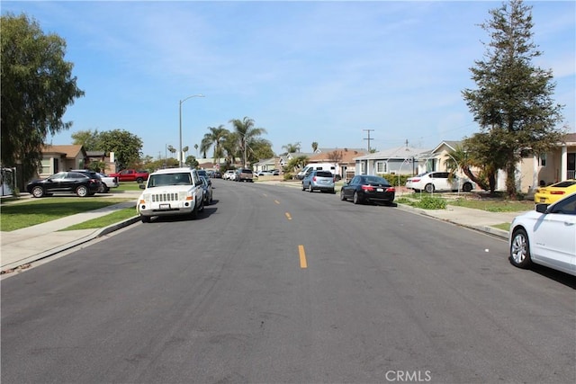 view of street with a residential view, curbs, street lighting, and sidewalks
