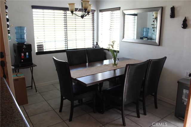 tiled dining space with baseboards and a chandelier