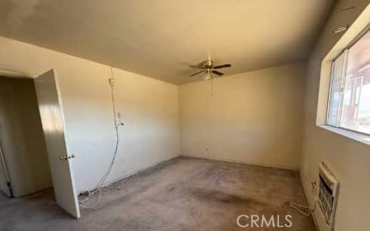 unfurnished room with heating unit, a ceiling fan, and unfinished concrete flooring