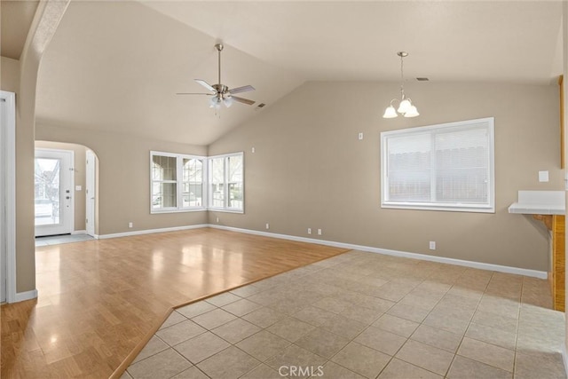 unfurnished living room featuring lofted ceiling, ceiling fan with notable chandelier, arched walkways, light wood finished floors, and baseboards