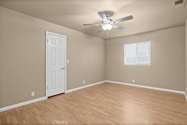 spare room with visible vents, ceiling fan, light wood-type flooring, and baseboards