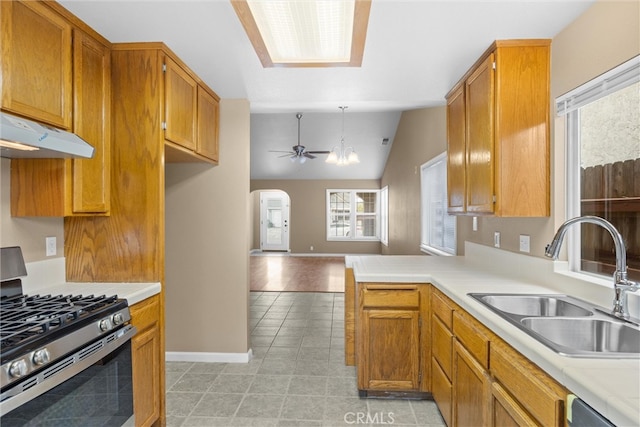 kitchen with arched walkways, a sink, light countertops, appliances with stainless steel finishes, and open floor plan